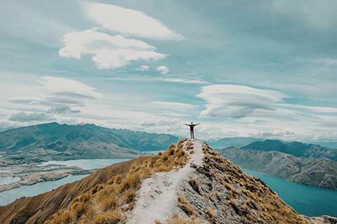 A person standing on a ridge representing financial planning and progress